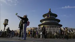 Para wanita berfoto selfie saat pengunjung mengunjungi Kuil Surga pada hari terakhir Hari Nasional China selama seminggu di Beijing, Kamis (7/10/2021). (AP Photo/Andy Wong)