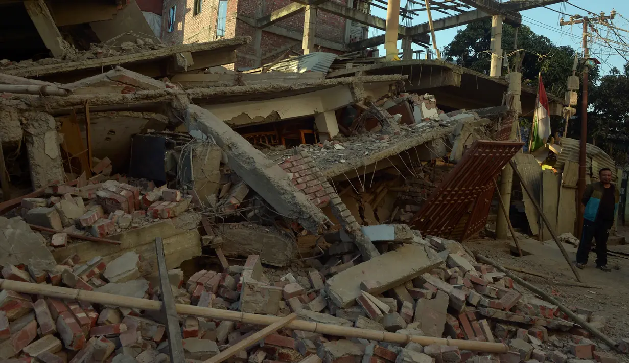 Warga mengamati bangunan yang rusak di Imphal setelah gempa bumi 6,7 SR mengguncang timur laut India, Senin (4/1). Delapan orang tewas sementara lebih dari 100 orang menderita luka-luka akibat gempa. (AFP PHOTO/Dibyangshu Sarkar) 