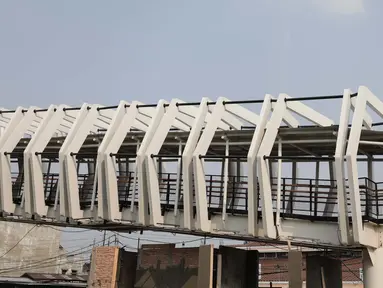 Pekerja menyelesaikan pembangun jembatan Skybridge di Ramangun, Jakarta, Kamis (4/7/2019). Pembangunan Skybridge sudah 98 persen rampung, yang nantinya akan menghubungkan Stasiun Kereta LRT Velodrome dengan halte busway Pemuda Rawamangun akan rampung akhir bulan ini. (Liputan6.com/Faizal Fanani)