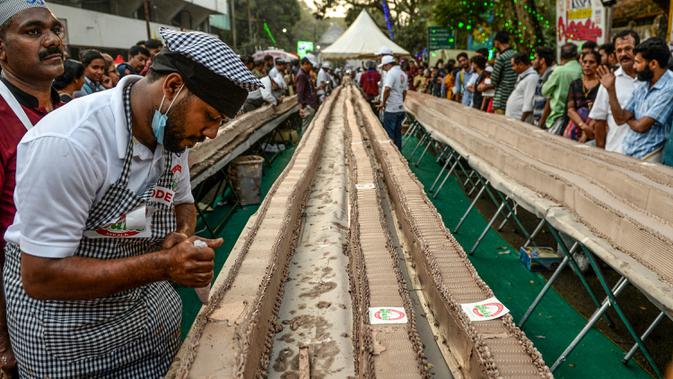 REKOR DUNIA BIKIN KUE - Seorang tukang roti menyelesaikan kue sepanjang 6,5 km untuk kue terpanjang dunia, di Thrissur di negara bagian Kerala, India selatan (15/1/2020). Ratusan pembuat roti dan koki di India selatan membuat kue terpanjang di dunia. (AFP/Arun Sankar)