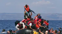 Seorang pengungsi mengangkat anaknya saat perahu mereka kempes di Pulau Lesbos, Yunani (13/9/2015). Menurut Organisasi Internasional untuk Migrasi (IMO) diperkirakan 309.000 orang telah tiba melalui laut di Yunani (REUTERS / Alkis Konstantinidis)