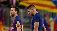 Pemain Barcelona, Lionel Messi dan rekan setimnya, Luis Suarez meninggalkan lapangan usai laga grup B Liga Champions melawan PSV Eindhoven di Camp Nou, Selasa (18/9). Messi tampak membawa bola yang dipakai dalam pertandingan itu pulang. (AFP/Josep LAGO)