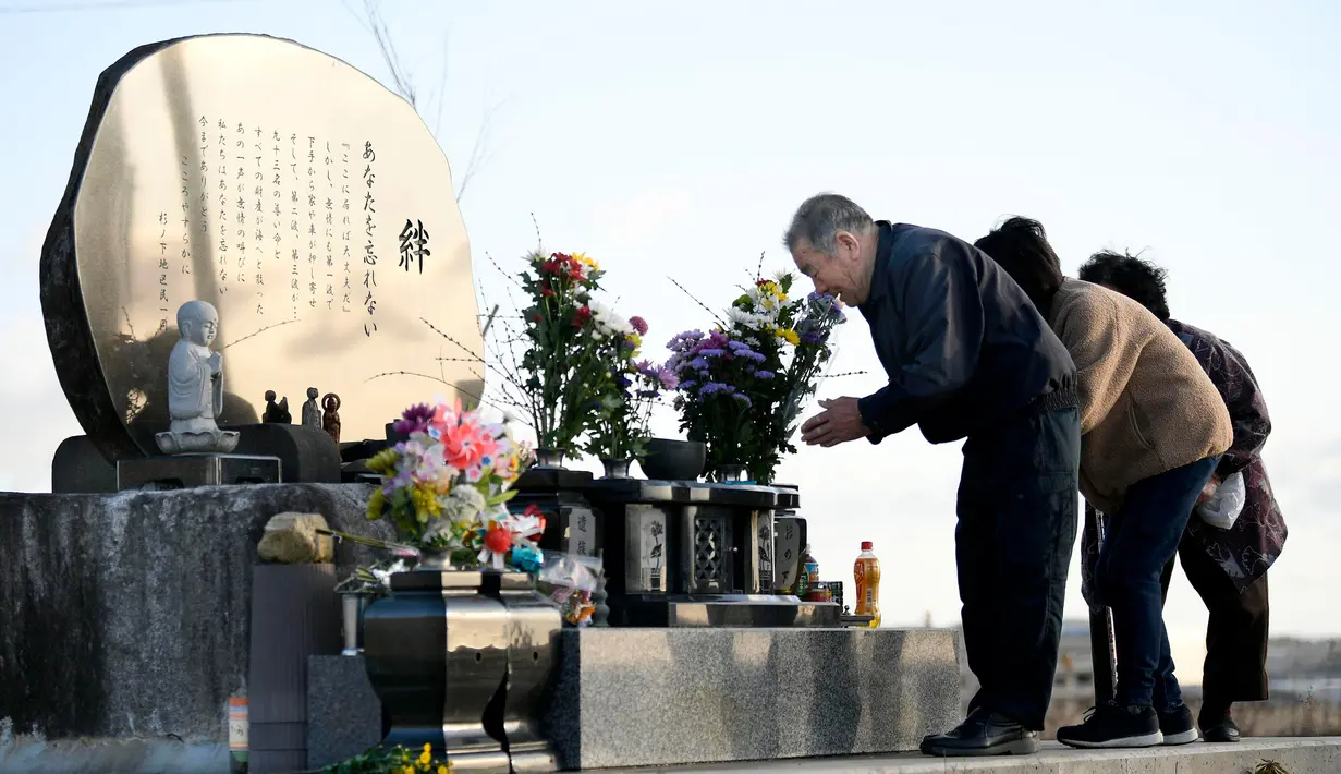 Anggota keluarga berdoa untuk para korban yang tewas dalam gempa bumi dan tsunami 2011 di depan monumen peringatan di Kesenuma, Jepang, Rabu (11/3/2020). Gempa 9,0 magnitudo yang menyebabkan tsunami pada 11 Maret 2011 itu menyebabkan sekitar 15 ribu orang tewas. (Kyodo News via AP)