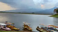 Perahu - perahu hanya bersandar di tepi Waduk Selorejo Malang yang suasananya masih tenang. Ini salah satu tempat wisata di Malang yang sudah buka lagi di tengah suasana pandemi (Liputan6.com/Zainul Arifin)
