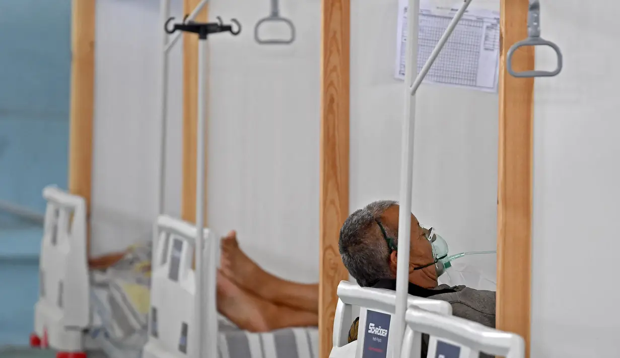 Pasien Tunisia menerima perawatan di gym yang diubah untuk menangani lonjakan infeksi COVID-19 di pusat kota Kairouan pada 4 Juli 2021. Tunisia tengah berjuang menghadapi tsunami COVID-19 sementara jumlah orang yang meninggal akibat virus corona terus melonjak tinggi. (FETHI BELAID/AFP)