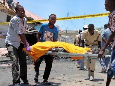 Sejumlah pria membawa korban yang tewas akibat serangan bom mobil di sebuah restoran di Mogadishu, Somalia, Rabu (5/4). Ledakan bom mobil tersebut telah menewaskan sejumlah orang. (AP Photo / Farah Abdi Warsameh)