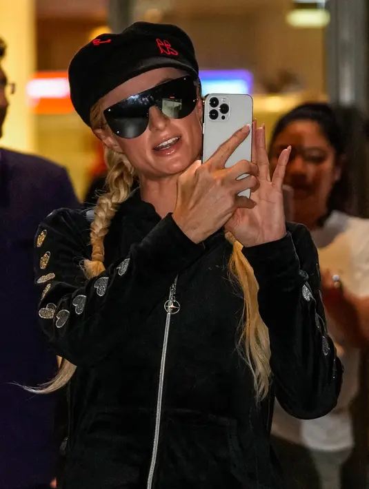 <p>Selebritas Amerika Serikat Paris Hilton berfoto dengan ponselnya saat tiba di Bandara Internasional Chhatrapati Shivaji, Mumbai, India, 19 Oktober 2022. Dia terlihat mengenakan jaket ritsleting beludru hitam dengan celana olahraga yang serasi. (AP Photo/Rafiq Maqbool)</p>