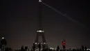 Sejumlah pengunjung berkumpul di dekat Menara Eiffel yang mengalami pemadaman sementara di Paris, Rabu (14/12). Pemadaman lampu Menara Eiffel ini sebagai simbol keprihatinan terhadap korban di Aleppo, Suriah. (AFP PHOTO/PHILIPPE LOPEZ)
