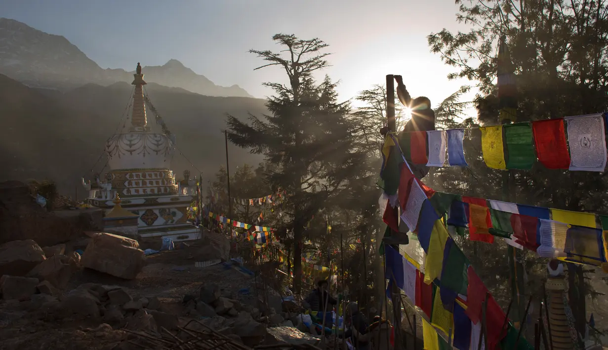 Seorang pria memasang bendera warna-warni atau yang disebut lungta pada hari ketiga Tahun Baru Tibet di Dharmsala, India (18/2). Bagi umat Buddha Tibet bendera itu berisi mantra yang mengandung doa. (AP/Ashwini Bhatia)