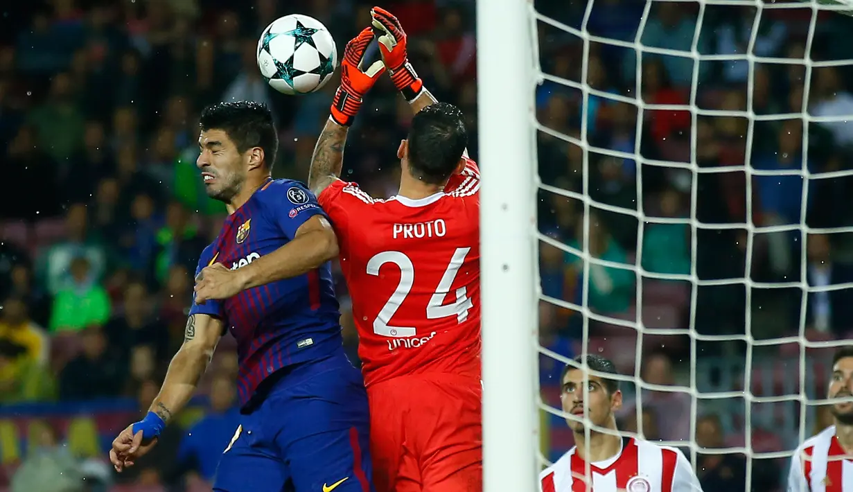 Pemain Barcelona, Luis Suarez menyundul bola di depan kiper Olympiakos, Silvio Proto dalam fase grup Liga Champions di Camp Nou Stadium, Kamis (19/10) dini hari. 10 pemain Barcelona sukses melumat Olympiakos 3-1. (AP/Manu Fernandez)