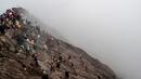 Sejumlah orang mencoba menangkap sajen yang dilemparkan ke kawah dalam ritual Yadnya Kasada di Gunung Bromo, Probolinggo, Jawa Timur, Kamis (18/7/2019). Ritual yang selalu berlangsung pada saat bulan purnama ini sudah dilangsungkan sejak abad ke-14. (JUNI KRISWANTO/AFP)