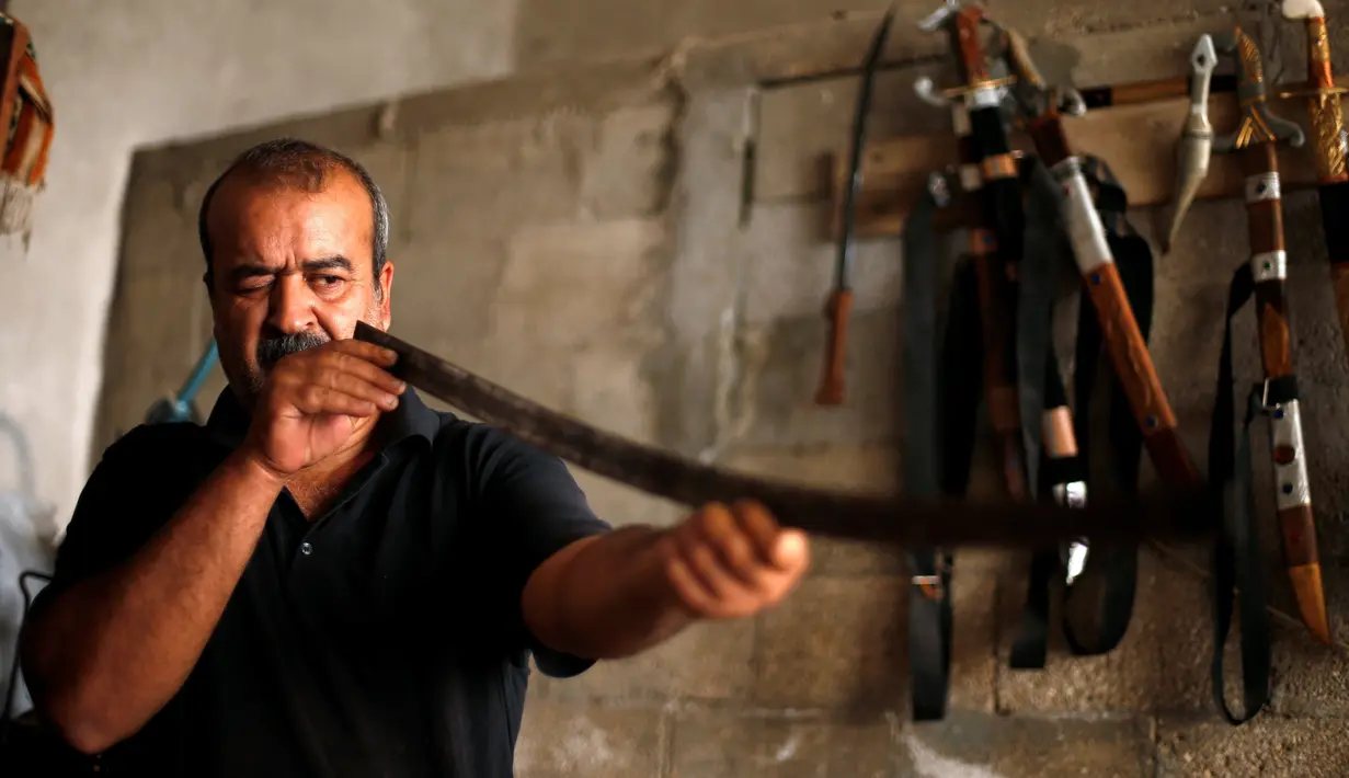 Pandai besi asal Palestina, Mueen Abu Wadi (45) memeriksa kelurusan pedang di bengkel kerjanya di Kota Gaza, Palestina (14/11). Mueen Abu Wadi meneruskan pekerjaan ayah dan kakeknya menjadi pembuat pedang. (REUTERS/Suhaib Salem)