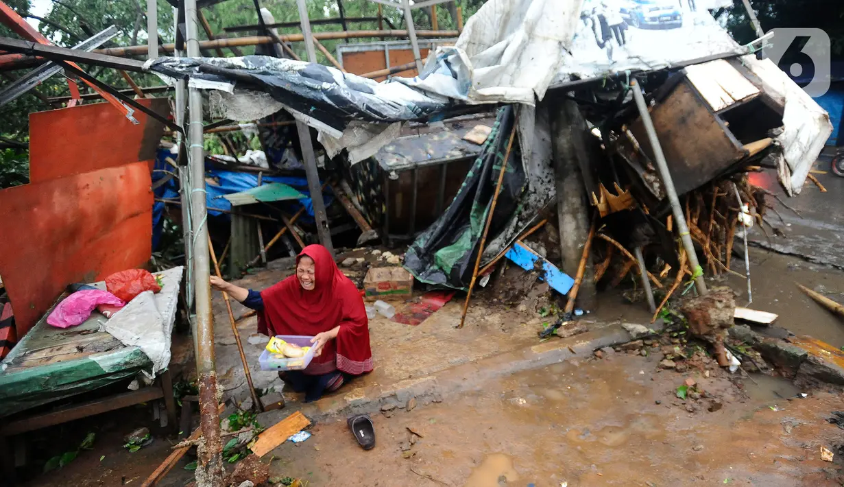 Seorang pedagang menangis usai warung kopi miliknya hancur tertimpa pohon tumbang di pinggir Jalan Raya Sawangan Depok, Minggu (09/10/20222). Hujan es disertai angin kencang yang terjadi di sejumlah kawasan di Depok pada Minggu sore mengakibatkan sejumlah bangunan dan pohon tumbang. (merdeka.com/Arie Basuki)