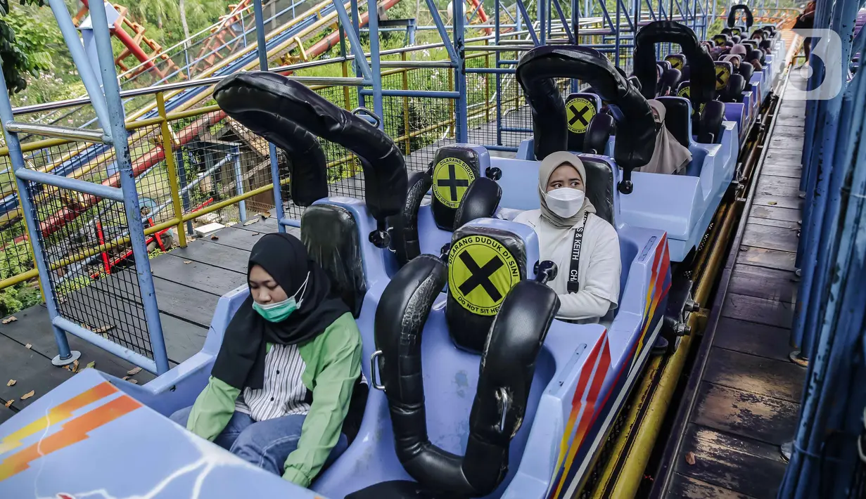 Para pengunjung menerapkan protokol kesehatan jaga jarak saat menaiki wahana bermain di Dunia Fantasi, Ancol, Jakarta, Minggu (10/10/2021). Pelonggaran PPKM level 3 di Jakarta membuat sejumlah tempat wisata kembali ramai didatangi pengunjung. (Liputan6.com/Faizal Fanani)