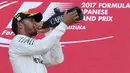 Lewis Hamilton meminum sampanye di atas podium merayakan kemenangannya pada GP F1 Jepang di Sirkuit Suzuka, Jepang, (8/10). Hamilton mengoleksi 306 poin atau unggul 59 poin dari Vettel yang gagal finis di Suzuka. (AP Photo / Toru Takahashi)