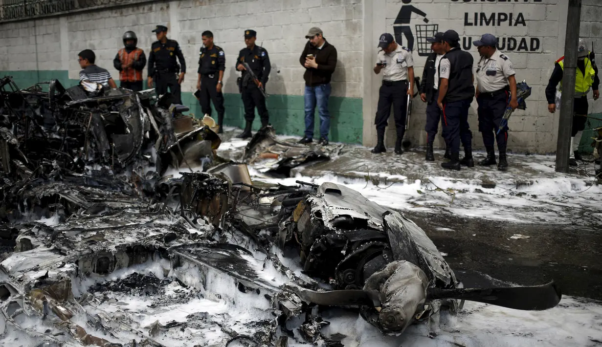 Petugas Polisi berjaga disamping bangkai pesawat yang hangus terbakar di Guatemala City, Guatemala, Sabtu (21/11/2015). Akibat kejadian ini dua awak pesawat dibawa kerumah sakit. (REUTERS/Jorge Dan Lopez)