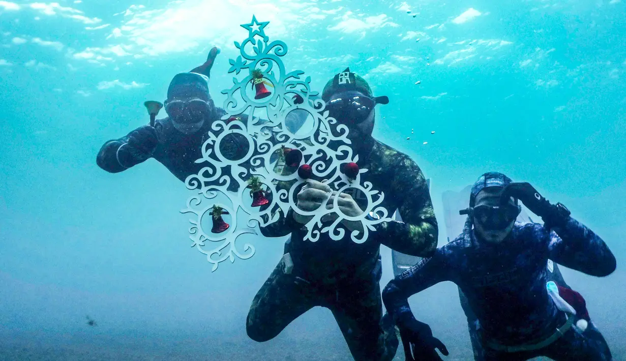 Penyelam berpose saat akan menempatkan pohon Natal di dasar laut lepas pantai Tripoli, Lebanon, Selasa (18/12). Hal ini dilakukan untuk menyambut Natal. (IBRAHIM CHALHOUB/AFP)