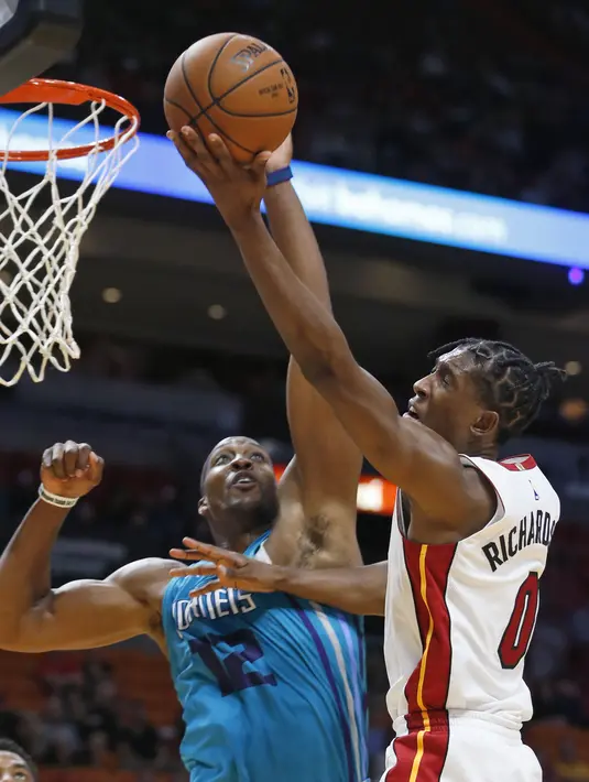 Aksi pebasket Miami Heat, Josh Richardson (kanan) memasukan bola saat dihalangi pebasket Hornets, Dwight Howard (kiri) pada laga NBA pre-season di American Airlines Arena, Miami, (9/10/2017). Miami Heat menang 109-106. (AP/Wilfredo Lee)