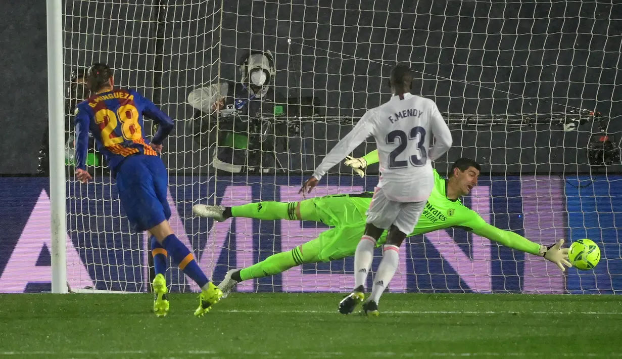 Bek Barcelona, Oscar Mingueza (kiri) melepaskan tendangan yang berbuah gol ke gawang Real Madrid yang dikawal Thibaut Courtois dalam laga lanjutan Liga Spanyol 2020/2021 pekan ke-30 di Alfredo di Stefano Stadium, Madrid, Sabtu (10/4/2021). Barcelona kalah 1-2 dari Real Madrid. (AFP/Javier Soriano)