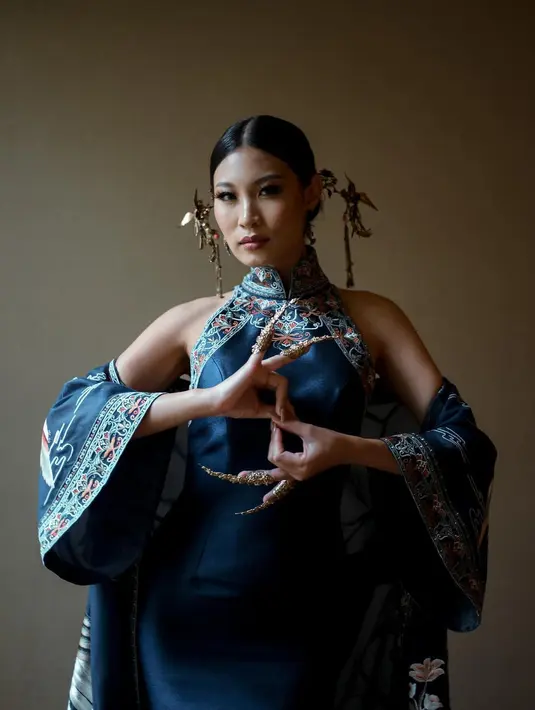 Patricia Gouw mengenakan cheongsam biru rancangan Hian Tjen. Cheongsam ini juga memiliki outer yang semakin membuat penampilan Patgouw megah, motif burung degnan warna emas terlihat luar biasa berpadu dengan tatanan rambut sleek look dan berbagai aksesori yang dikenakannya. Foto: Instagram.