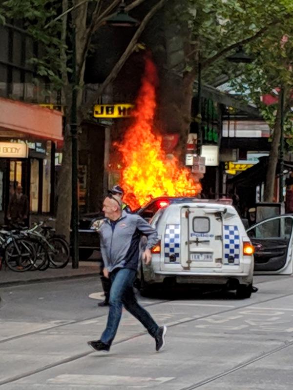 Seorang pria berlari dekat kendaraan yang terbakar setelah pengemudi menghentikan kendaraan dan menikam sejumlah orang di pusat Kota Melbourne, Australia, Jumat (9/11). (Chris Newport/Courtesy of Chris Newport via Instagram/AFP)