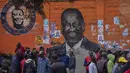 Warga berkumpul untuk membahas pemilu di depan mural calon presiden Raila Odinga, di daerah Kibera, Nairobi, Kenya, Kamis, 11 Agustus 2022. Rakyat Kenya menunggu hasil pemilihan presiden yang berlangsung ketat namun tenang di mana jumlah pemilih lebih rendah daripada biasanya. (AP Photo/Ben Curtis)