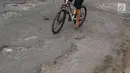 Pengendara sepeda menghindari jalan berlubang di kawasan Gas Alam, Depok, Jawa Barat, Kamis (4/10). Hingga kini kondisi jalan rusak di kawasan tersebut tidak diperbaiki oleh pihak terkait. (Liputan6.com/Immanuel Antonius)