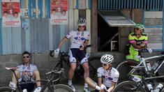 Para pebalap sepeda beristirahat sebelum melakukan start ulang di Titik Nol Kilometer Painan, Kabupaten Pesisir Selatan, Sumatra Barat saat Etape 1 Tour de Singkarak, Sabtu (3/10/2015). (Bola.com/Arief Bagus)