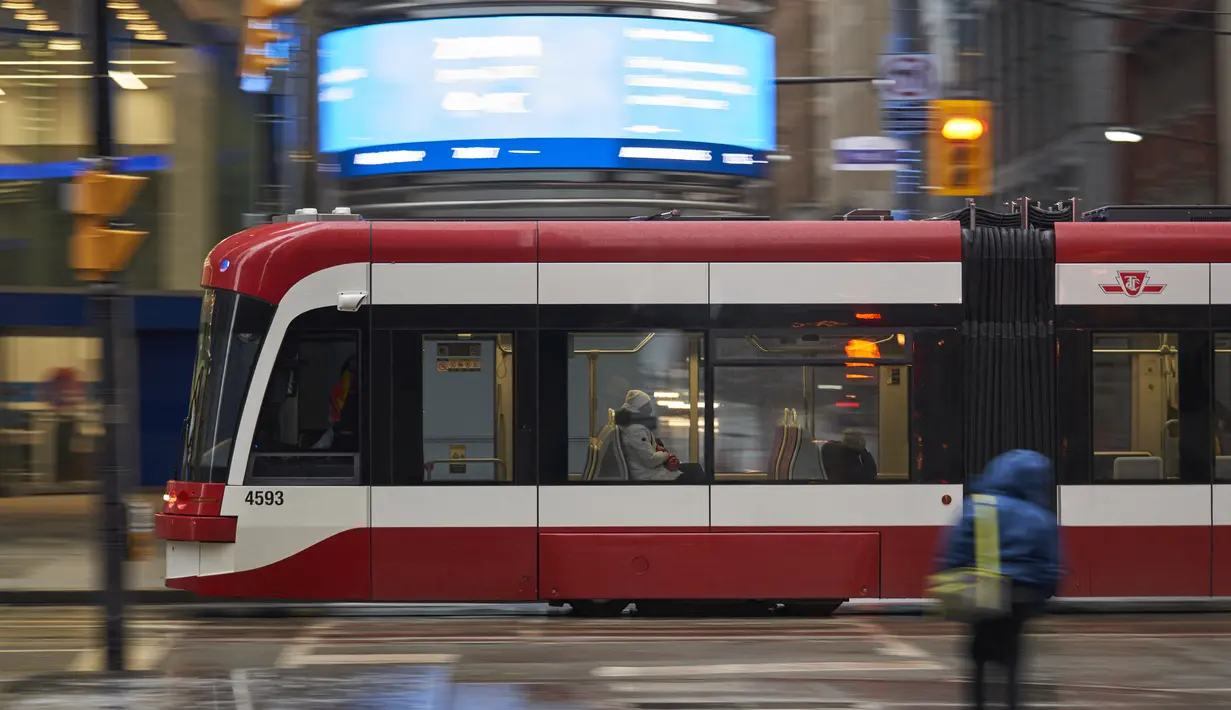 Seorang wanita mengenakan masker menaiki bus melalui distrik keuangan di Toronto, Ontario, Rabu (5/1/2022). Salah satu provinsi di Kanada tersebut memberlakukan pembatasan baru mulai hari ini untuk memperlambat penyebaran Covid-19 varian Omicron. (Geoff Robins / AFP)