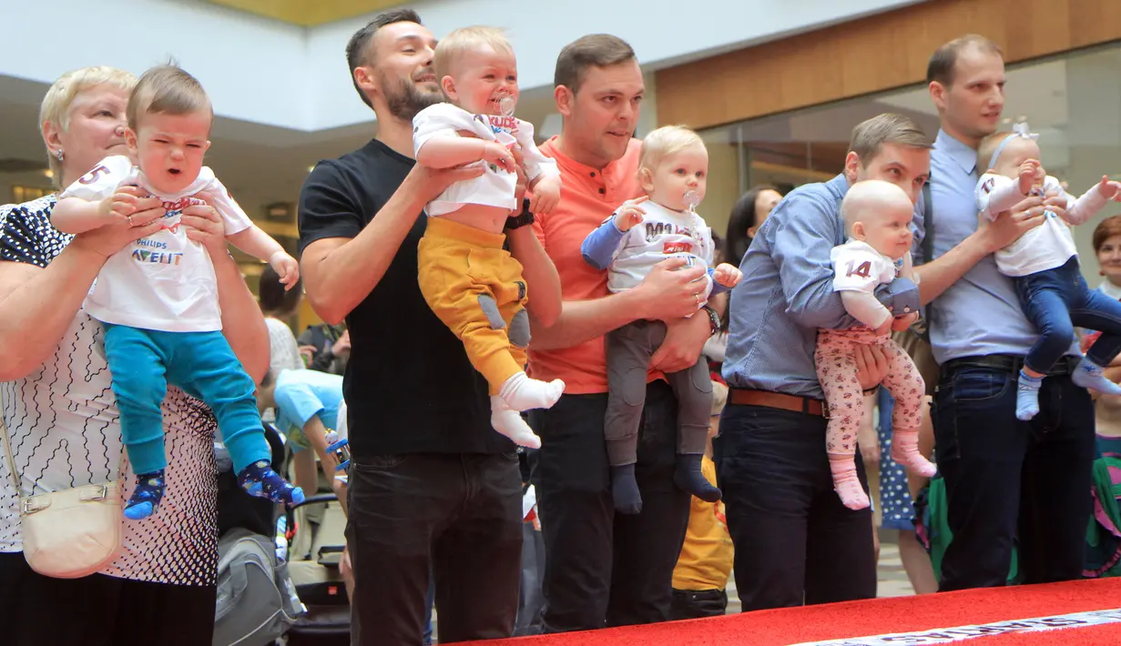 Sejumlah bayi didampingi ayah mereka bersiap mengikuti lomba merangkak untuk memperingati Hari Anak Internasional di Vilnius, Lithuania, Kamis (1/6). Orang tua memberikan iming-iming benda kesukaan buah hatinya saat mengikuti lomba. (Petras Malukas/AFP)