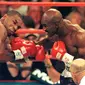 Mike Tyson dan Evander Holyfield kembali berduel di MGM Grand Garden Arena, Las Vegas pada 28 Juni 1997. Akan tetapi, laga akbar ini harus dihentikan pada ronde ketiga, karena Tyson menggigit kuping Holyfield. (AFP/JOHN GURZINSKI)