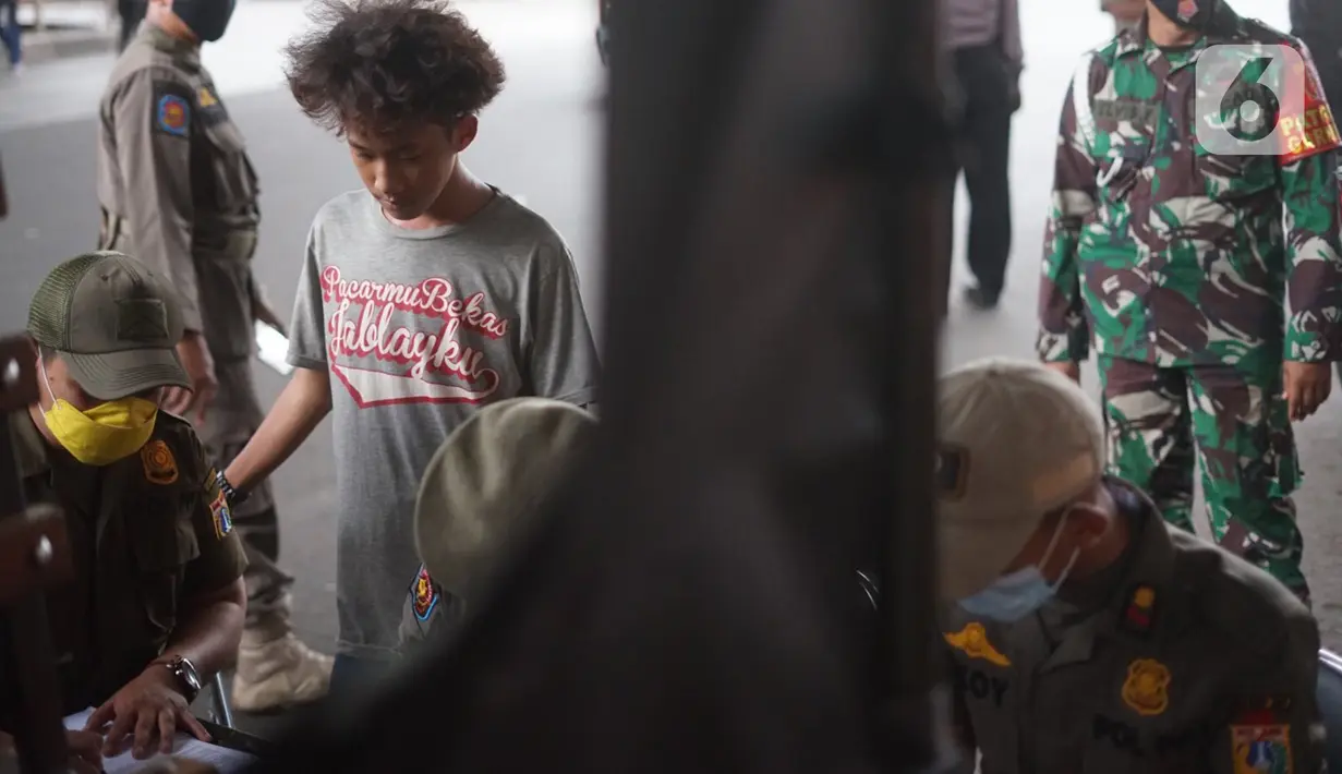 Petugas mendata warga pelanggar Operasi Yustisi Pencegahan Covid-19 di kawasan Kampung Melayu, Jakarta Timur, Senin (16/11/2020). Operasi tersebut digelar guna menyadarkan masyarakat akan pentingnya penggunaan masker di tengah pandemi Covid-19. (Liputan6.com/Immanuel Antonius)