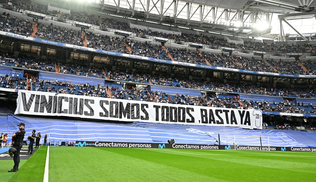 Banner besar juga terbentang di salah sisi tribun Santiago Bernabeu. Tulisannya mengartikan, “Kami semua adalah Vinicius. Cukup sampai di sini”. (Photo by JAVIER SORIANO / AFP)