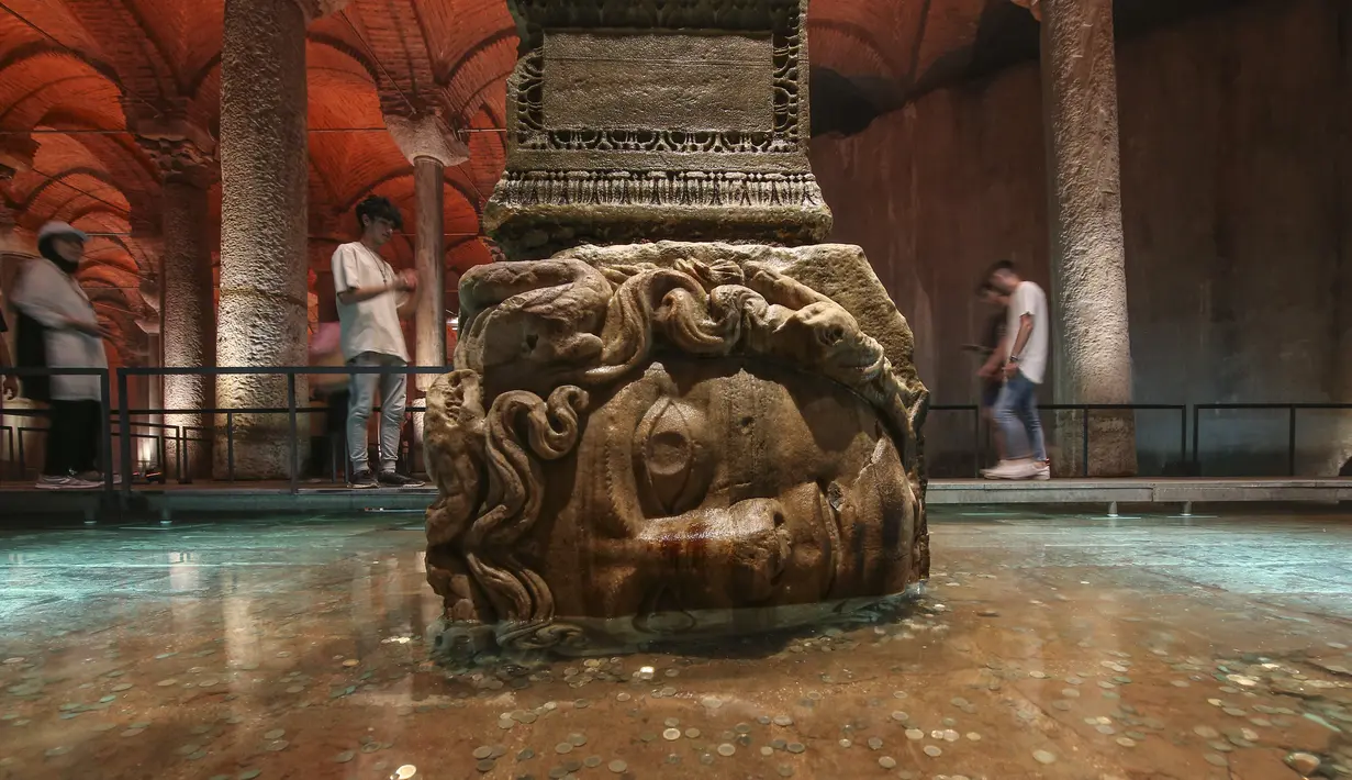 Pengunjung berjalan melewati kolom Medusa di Basilika Cistern era Bizantium di Istanbul, Turki, Rabu, 27 Juli 2022. Tidak jelas dari mana dua kepala Medusa ini berasal dan kapan dibawa masuk dan dipasang di Basilica Cistern. (AP Photo/Emrah Gurel)