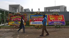 Pejalan kaki melintasi karangan bunga ucapan selamat untuk Laudya Cynthia Bella dan Engku Emran di lokasi resepsi pernikahan kawasan Dago, Bandung, Minggu (8/10). Bella dan Emran resmi menikah pada 8 September 2017. (Liputan6.com/Herman Zakharia)