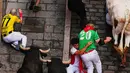 Pengunjung festival terjatuh di depan banteng-banteng aduan Victoriano del Río saat acara lari banteng ketiga di festival San Fermín di Pamplona, Spanyol, Kamis, 9 Juli 2026. (AP Photo/Miguel Oses)
