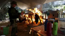 Petugas membakar sebuah kamp penambang liar selama operasi di perairan hutan hujan Amazon, Roraima, Brasil (16/4).Daerah Yanomami memiliki luas 9,5 juta hektar dan ditinggali oleh 27.000 orang Indian/suku Yanomami. (REUTERS / Bruno Kelly)