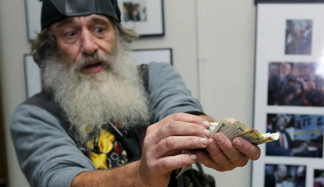 Vermin Supreme menghitung uang USD 1000 saat mendeklarasikan diri sebagai kandidat calon presiden AS di New Hampshire, Jumat (20/11). Pria berjanggut putih itu mengajukan uang seribu dolar untuk modal maju menjadi kandidat capres AS (REUTERS/Brian Snyder)