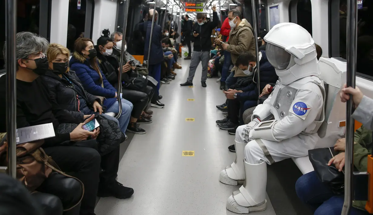Seorang pria berpakaian astronaut naik metro sebagai bagian dari kampanye untuk mempromosikan Pameran Luar Angkasa NASA di Istanbul, Turki, pada 4 Desember 2021. Pameran ini akan menampilkan modul khusus dari luar angkasa dan puluhan instrumen berteknologi tinggi. (AP Photo/Emrah Gurel)