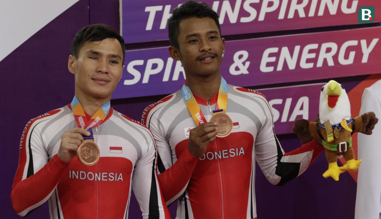 Pebalap sepeda Indonesia, Herman Halawa dan Pradana Diwan, saat menerima medali pada Asian Para Games di Velodrome, Jakarta, Kamis (11/10/2018). Pasangan Indonesia ini meraih perunggu di nomor trek Individual Pursuit B putra. (Bola.com/M Iqbal Ichsan)