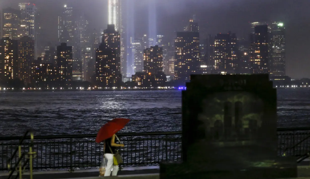 Seorang wanita berjalan di depan seni cahaya 'Tribute in Light' di Lower Manhattan, New York , Kamis (10/9/2015). Masyarakat akan menggelar peringatan terkait tragedi 9/11. (REUTERS / Eduardo Munoz)