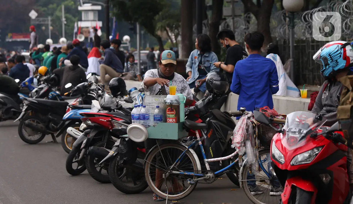 Pedangang membuat minuman untuk massa aksi saat demo penolakan omnibus law di kawasan Patung Kuda, Jakarta, Selasa (20/10/2020). Para pedagang kaki lima memanfaatkan moment aksi massa untuk mencari ke untungan meskipun sangat membahayakan bagi keselamatan mereka. (Liputan6.com/Angga Yuniar)