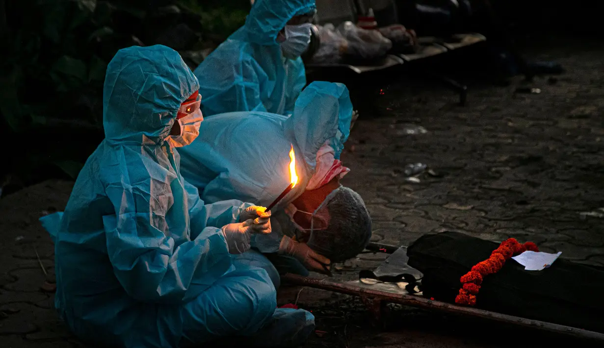 Kerabat dengan mengenakan alat pelindung diri melakukan ritual selama kremasi seseorang yang meninggal karena virus corona COVID-19 di Gauhati, India pada 28 September 2020. (AP Photo/Anupam Nath)