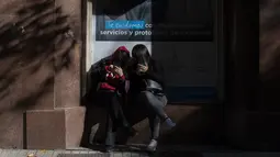 Para perempuan melihat ponsel mereka saat menunggu di kantor layanan kesehatan di pusat kota Santiago, Sabtu (12/6/2021). Ibu kota Chile mengembalikan tindakan karantina di tengah meningkatnya kasus COVID-19, meskipun hampir 60% warga negara itu sudah divaksinasi sepenuhnya. (AP Photo/Esteban Felix)