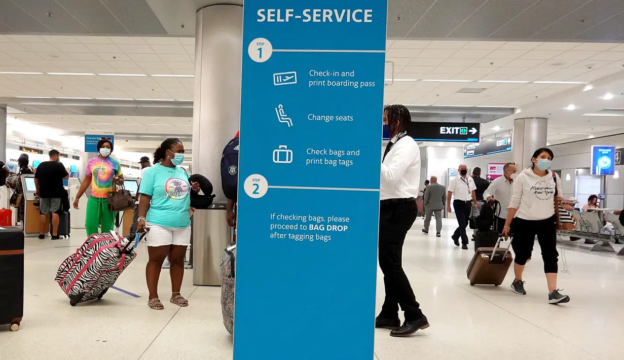 Wisatawan berjalan melalui Bandara Internasional Miami, Florida, Senin (20/9/2021). AS mengatakan mulai awal November akan melonggarkan pembatasan virus corona untuk para pengunjung dari luar negeri yang sudah divaksin lengkap dan menjalani tes serta pelacakan kontak. (Joe Raedle/Getty Images/AFP)
