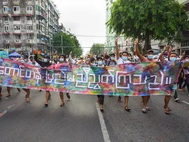 Pengunjuk rasa memberi hormat tiga jari sambil memegang spanduk bertuliskan, "Bukit dan Wilayah Tengah bersatu" di Yangon (3/6/2021). Demonstran pro-demokrasi turun ke jalan di kota-kota di Myanmar untuk mengecam militer, menandai empat bulan sejak menggulingkan pemerintah terpilih. (AFP/STR)