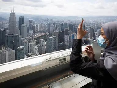 Seorang turis dengan mengenakan masker mengambil gambar dari dek obseravsi di Menara Kuala Lumpur di Kuala Lumpur, Rabu (1/7/2020). Malaysia memasuki pelonggaran Perintah Kontrol Gerakan (MCO) setelah tiga bulan pembatasan karena virus corona Covid-19. (AP Photo/Vincent Thian)