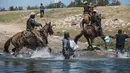 Petugas berusaha menahan para migran saat mereka menyeberangi Rio Grande dari Ciudad Acuña, Meksiko, ke Del Rio, Texas, Minggu (19/9/2021). Ribuan migran Haiti telah tiba di Del Rio, Texas, saat pihak berwenang berupaya menutup perbatasan untuk menghentikan arus migran.(AP Photo/Felix Marquez)