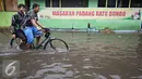 Warga mengenakan sepeda melintasi banjir di kawasan Sunter, Jakarta, Kamis (25/2). Hujan deras yang mengguyur Jakarta serta sistem drainase yang buruk menjadi penyebab banjir sehingga mengganggu aktivitas warga. (Liputan6.com/Immanuel Antonius)