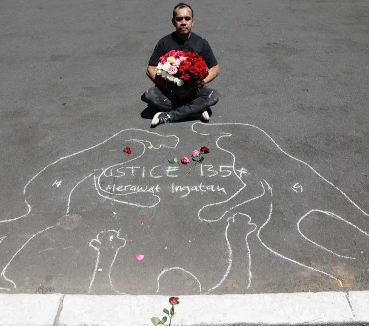 Seniman dari Malang Performance Art Community, Muhmin Ahmad, berdiri tegak di bawah terik matahari. Kedua tangannya menjunjung seikat bunga mawar. Ia berada di depan Balai Kota Malang pada Kamis (10/8/2023).